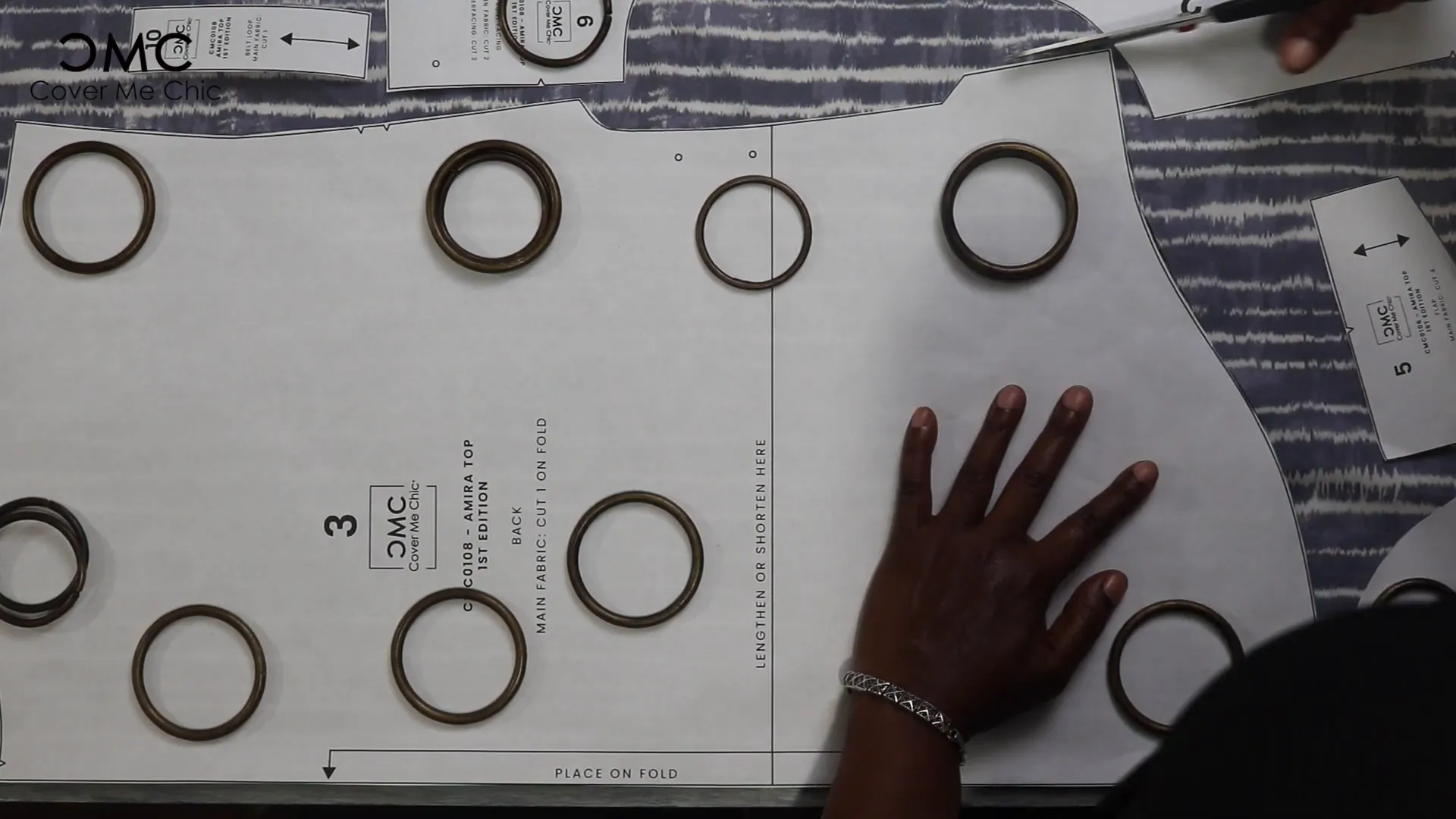 Laying out the Amira Top sewing pattern on fabric with weights