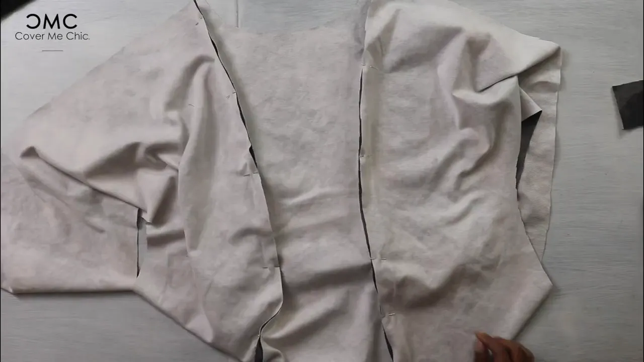Pinned fabric bodice pieces laid flat showing notches and seam lines on a work surface.
